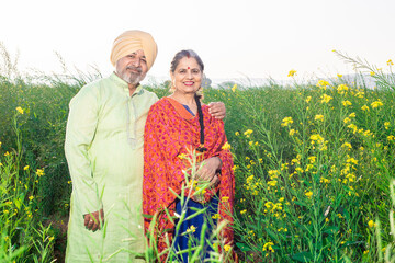 Wall Mural - Portrait of Happy senior Punjabi sikh couple standing together at agriculture field. Looking at camera.