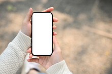 A Woman Holding A Smartphone White Screen Mockup Over Blurred Street In Background.