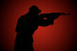 © Arsentyev Vladimir - Silhouette of a military man with a rifle at night on a red background. Side view