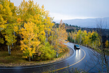 A Car Drives A Curvy Mountain Road In The Rain, Aspen Trees In Golden Fall Colors