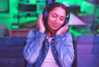 Music headphones, relax and woman in home streaming radio or podcast at night in green neon light. Hacker, it programmer and happy female coder listening and enjoying song, audio or sound in house.