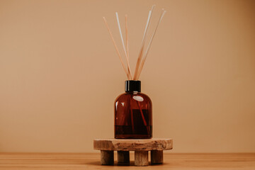 essential oil diffuser with sticks standing on wooden platform. beige background. copy space. templa