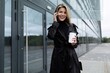 © Ivan Traimak - happy joyful smiling caucasian woman in black business clothes talking on the phone with a cup of coffee in her hands outside