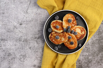 Fluffy buttermilk pancakes with blueberries on a plate on a dark background. Top view, flat lay