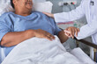 © Seventyfour - Close up of senior black woman on hospital bed with young nurse supporting her