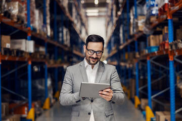 Wall Mural - A smiling warehouse supervisor is adding orders on tablet.