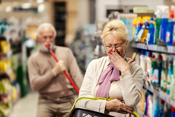 Wall Mural - A senior woman is laughing at her husband who is singing and goofing around in supermarket.