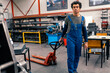 © DusanJelicic - A mixed race worker in overalls pulls a small forklift for transport