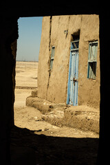 view of house wall and blue door. shadow frames perspective. abandoned village near luxor egypt