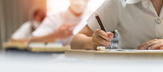 Wall Mural - Exam at school with student's taking educational admission test in class, thinking hard, writing answer in university classroom, education and world literacy day concept