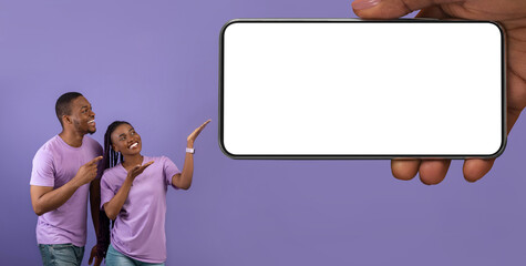 Poster - Cheerful Black Couple Pointing At Huge Blank Cellphone In Big Female Hand