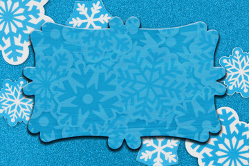 Wall Mural - Blank wood sign on snowflakes on blue glitter material winter background