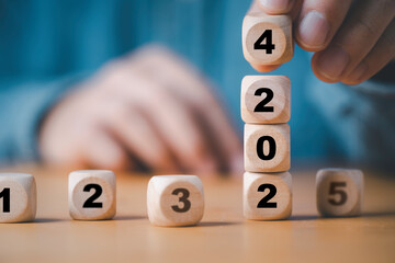 Wall Mural - businessman stacking 2024 year which print screen on wooden block cube for preparation merry christm