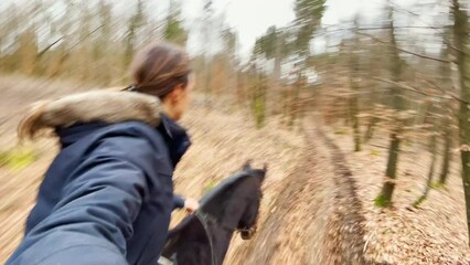 Wall Mural - SELFIE: Young Caucasian woman leads her horse along a forest trail on a cold autumn day. Happy female horseback rider gallops across the quiet woods in late fall. Selfie of woman horseback riding.