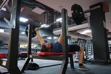 
February 21, 2023 Ukraine, Dnipro.
Barbell Bench Press. A Young Athlete On A Simulator In A Supine Position Loads The Muscles Of His Arms And Chest. Training Of Muscle Groups Of The Upper Body. Gym