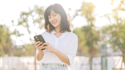 Portrait beautiful young asian woman with smart mobile phone around outdoor nature view in a sunny summer day