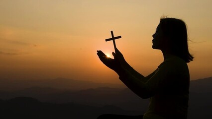 Wall Mural - Silhouette of a praying woman looking at the sunset pious Her hair was blown by the wind in the sun. believe in good girl dreaming of love Thinking and praying to heaven Concepts of Religion, Spiritua