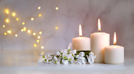 Wall Mural - Angels, snowdrops flowers and candles on table, blurred abstract background. Religious church holiday. symbol of faith in God, Christianity Feast. Romantic relaxation composition