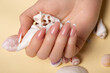 Hands with long artificial nails with french manicure holding seashells
