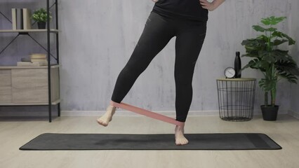 Wall Mural - young woman doing exercises with elastic band at home