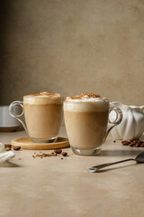 Two glass cups with coffee drink, latte with milk foam and cinnamon