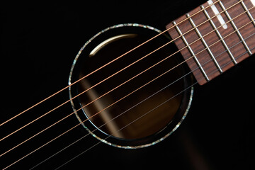 Guitar sound hole and strings shot from above in flat lay style. Beautiful black acoustic guitar in close up