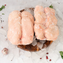 Wall Mural - frozen raw chicken breast with vegetables on the ice on wooden board on the.gray rock background