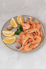 Wall Mural - frozen raw shrimps with lemon and garlic on a gray rock  background 