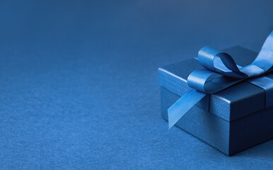 Part of Luxury gift box with a blue bow on dark blue. side view monochrome close up. Fathers day or Valentines day gift for him. Corporate gift concept or birthday party. Festive sale copy space