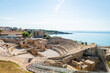 Wide-angle view of the ruins of the Roman amphitheater in Tarragona, built in the 2nd century AD, with the Mediterranean Sea in the background.