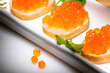 Orange caviar on butter rolls decorated with parsley on white rectangular plate is illuminated by white light.
