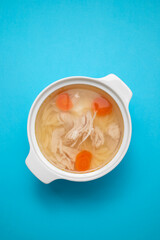 Wall Mural - bowl of chicken broth with chicken and carrot in blue