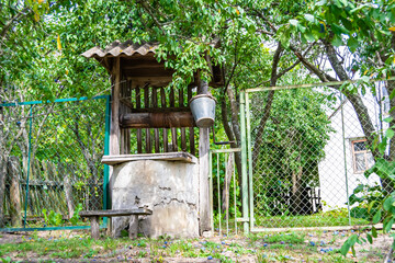 Wall Mural - Old well with iron bucket on long forged chain for clean drinking water