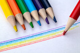 Fototapeta Tęcza - Bright сolored pencils on a white paper background. Blots. Rainbow. Close up. Macro.