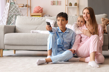 Canvas Print - Mother with her little children watching cartoons on TV at home