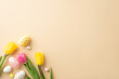 Easter concept. Top view photo of colorful easter eggs and tulips on isolated pastel beige background with copyspace