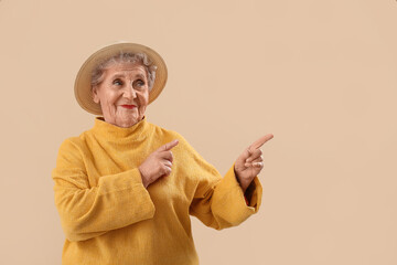 Sticker - Senior woman in hat pointing at something on beige background