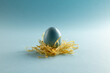 Image of blue easter egg in straw and copy space on blue background