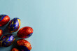 Image of multi coloured chocolate easter eggs with copy space on blue background
