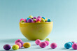 Image of multi coloured easter eggs in bowl with copy space on blue background