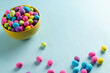 Image of multi coloured easter eggs in bowl with copy space on blue background