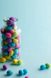 Image of multi coloured easter eggs in clear jar with copy space on blue background