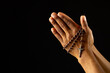 Image of close up of hands of african american woman praying with rosary