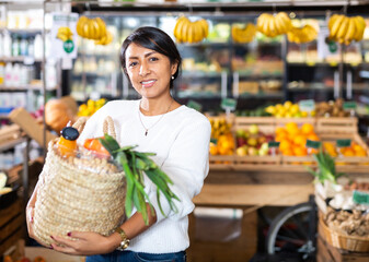 Portrait of happy woman with bag of groceries in supermarket