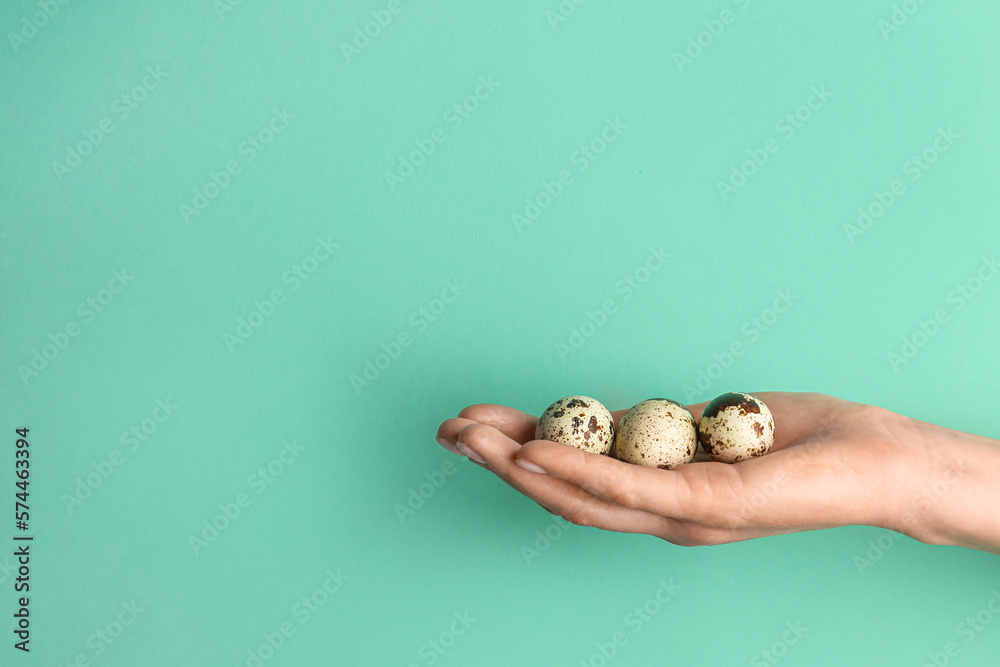 Woman holding quail eggs on turquoise background