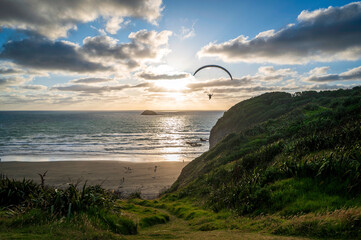 Paragliding fun at sunset, Muriwai Beach, near Auckland New Zealand