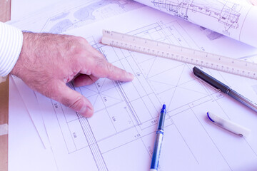 Mature architect hand points measure on an architecture plan.