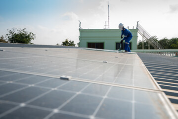 Wall Mural - Man using a mop and water to clean the solar panels that are dirty with dust and birds' droppings to improve the efficiency of solar energy storage