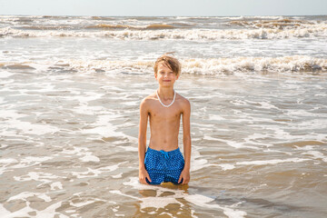 Wall Mural - Young Child Preteen Boy Standing in the Surf at the Beach on a Sunny Day