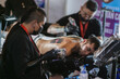 © Kaincloud - man and woman tattoo artists doing work on the back of a young man, I use biosafety elements, art fusion